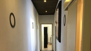A hallway with a speckled floor, white walls, and a ceiling with recessed lighting.