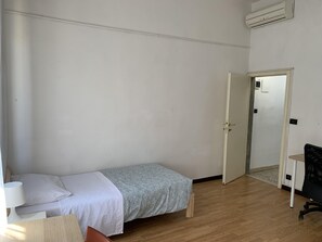 Une petite pièce simple, avec un lit, un bureau et une chaise.