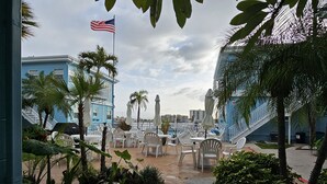 An outdoor seating area with white plastic chairs and tables, surrounded by plants and a pathway. - Mandalay Bay Front Studio (Clearwater)