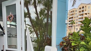 A residential building with a blue exterior, a white mailbox, and a small garden with various plants and a potted plant with red flowers. - Mandalay Bay Front Studio (Clearwater)