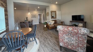 A spacious living room with a dining area, a ceiling fan, a television, and a fireplace. - Oversized 1BR/1BA home near Hospital in Temple, TX  NEW CONSTRUCTION - monthly! (Temple)