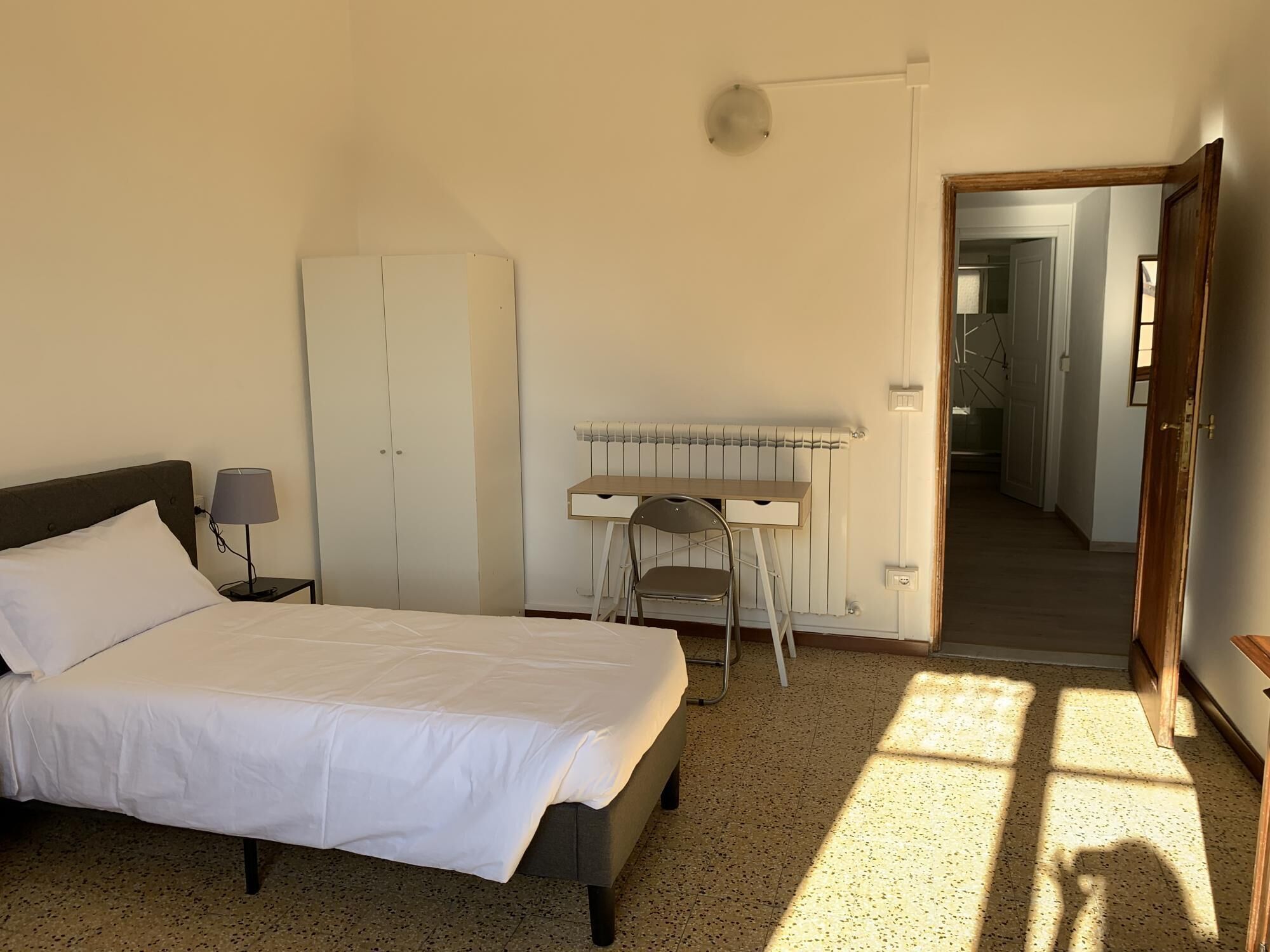 A bedroom with a bed, a desk, a chair, and a wardrobe.