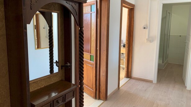 A hallway with wooden doors and a mirror.