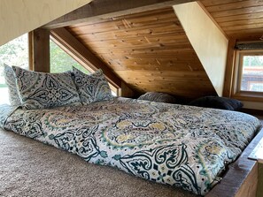 A loft-style bedroom with a wooden ceiling and large windows. - Waterfront Cabin in the center of Thompson Falls!! (Thompson Falls)