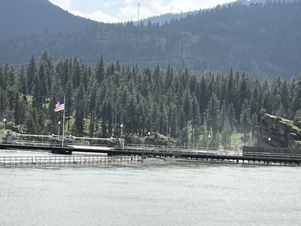 A bridge with an American flag, surrounded by dense forest and mountains. - Waterfront Cabin in the center of Thompson Falls!! (Thompson Falls)