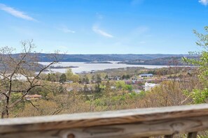 A view from a wooden deck overlooking a lake, with houses and trees in the foreground and hills in the distance. - The Greenview Manor - Lake Views (Kimberling City)