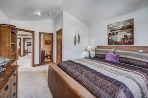 Ein Schlafzimmer mit einem großen Bett, einer Holzkommode, einem Nachttisch und einem Bild an der Wand.