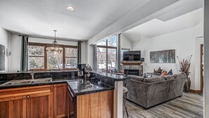 A spacious kitchen with a large island, wooden cabinets, and a stone countertop. There is a built-in oven and a large window providing natural light. - The Oak Lane Chateau: with Private Hot Tub, Close to Golf, Free Ski Shuttle!! (Breckenridge)