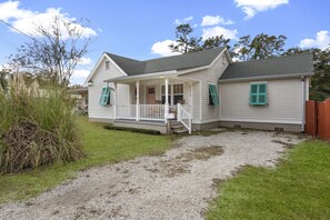 A single-story house with a porch, a small front yard, and a gravel driveway.