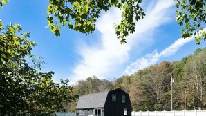 Eine schwarze Scheune mit Veranda und umzäunter Hof.