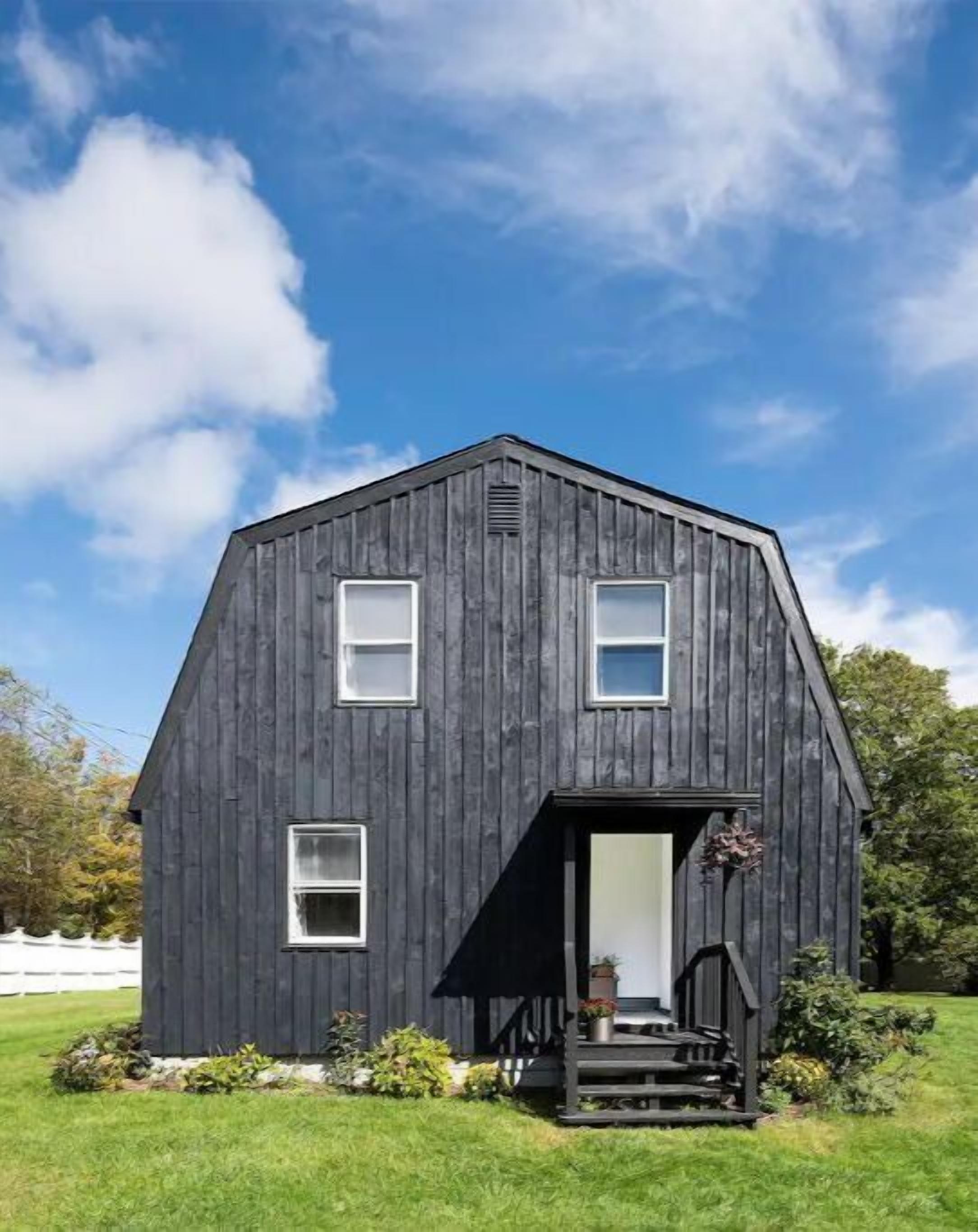 A dark wooden barn-style building with a front porch and two windows.