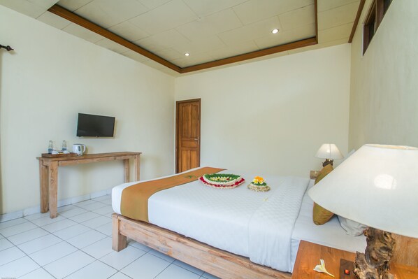 A bedroom with a bed, bedside table, lamp, and a television on the wall.