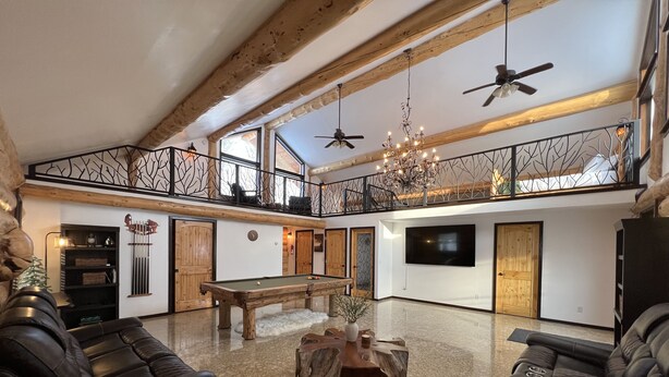 A spacious living area with a pool table, leather sofas, a chandelier, and a TV. - Grand Spruce Lodge, Lakefront near Talkeetna & Denali State Park (Trapper Creek)