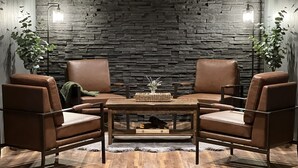A room with a stone wall, two leather chairs, a wooden table, and two floor lamps. - Grand Spruce Lodge, Lakefront near Talkeetna & Denali State Park (Trapper Creek)