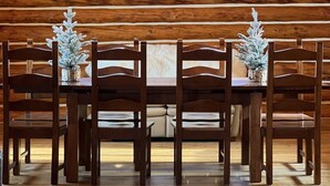 A dining area with a wooden table and chairs, a chandelier, and a view through a skylight. - Grand Spruce Lodge, Lakefront near Talkeetna & Denali State Park (Trapper Creek)