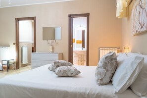 Ein Schlafzimmer mit einem großen Bett, zwei Nachttischen, einer Kommode, einem Spiegel und einem Heizkörper.