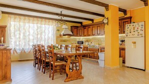 Una cocina con armarios de madera, una mesa de comedor con sillas y un refrigerador.