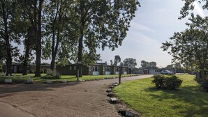Een rij laagbouwgebouwen met een grindpad en een gazon met bomen.