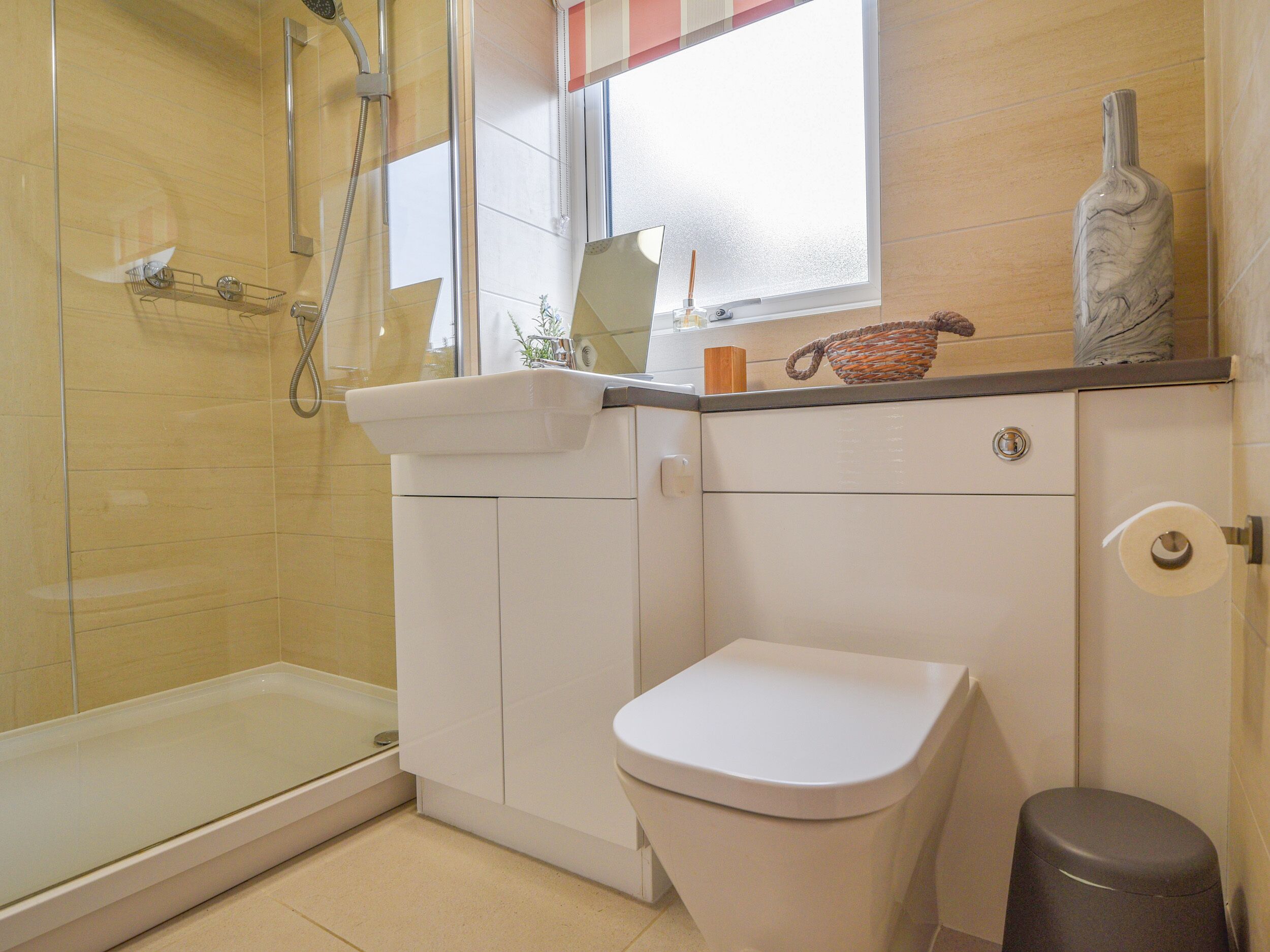 A bathroom with a glass shower enclosure, a white toilet, and a sink with a mirror above it.