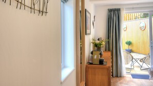 A hallway with a wooden desk, a vase with flowers, and a window with curtains. - Blue Neptune (Lyme Regis)