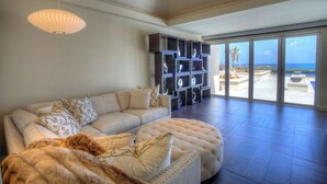 Amplia sala de estar con un sofá grande, una manta suave y un mueble decorativo con estantes.