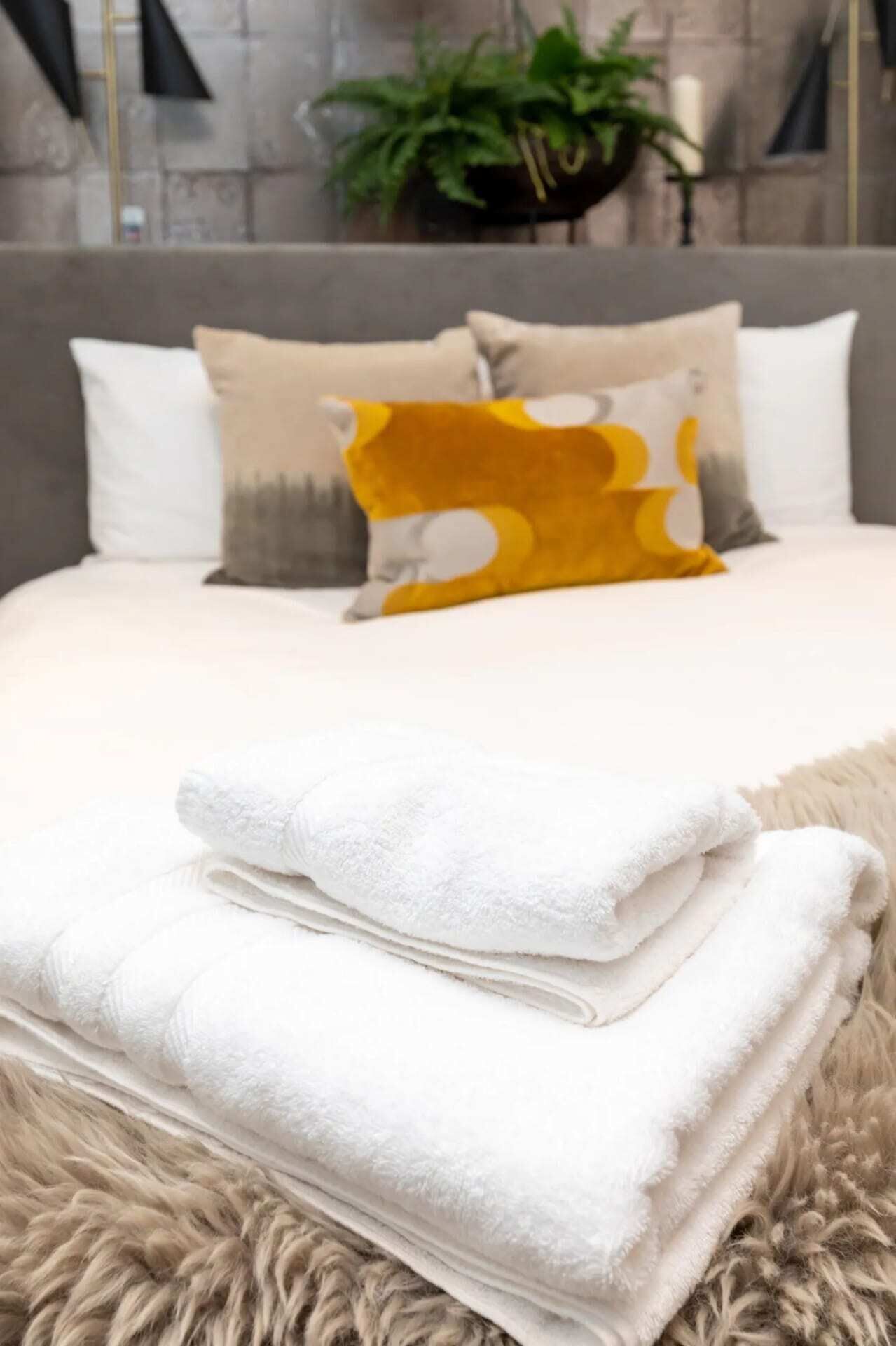 A neatly made bed with a fluffy white blanket and a folded white towel on top.