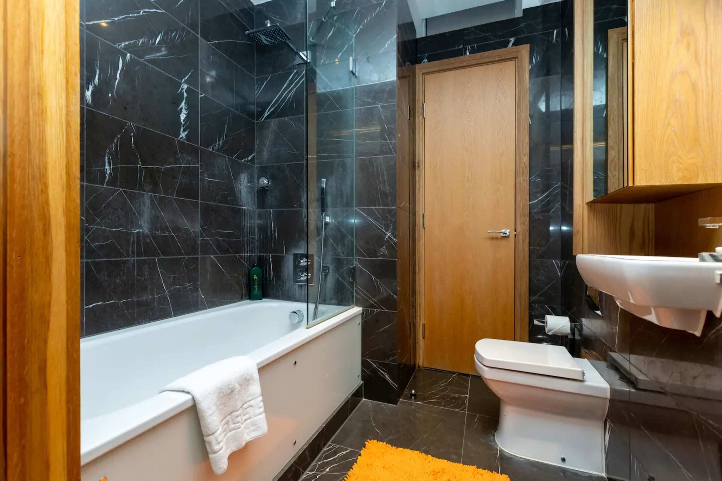 A modern bathroom with a bathtub, toilet, and shower area.