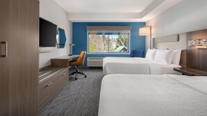 A hotel room with a bed, a desk, a chair, a TV, and a window with a view of trees. - Holiday Inn Express & Suites Courtenay - Comox by IHG (Courtenay)