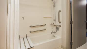 Une salle de bain équipée d’une baignoire, de barres d’appui et d’un pommeau de douche.