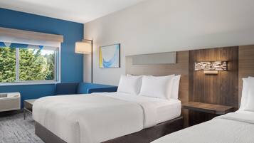 Habitación de hotel con dos camas, un ventanal grande, una lámpara de pared y vistas a zonas verdes.
