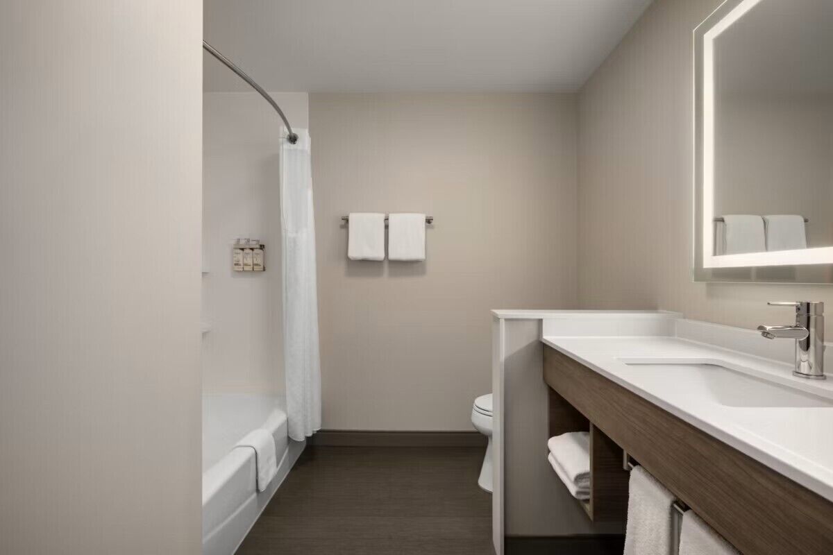 Une salle de bain moderne équipée d’une baignoire, de toilettes et d’un meuble-lavabo avec un miroir.