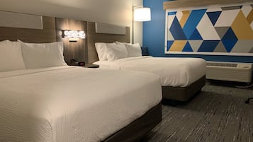 A hotel room with two beds, a wall-mounted lamp, a geometric wall decoration, and an air conditioning unit.