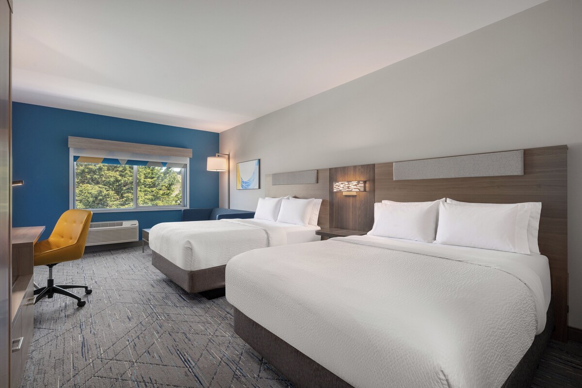 A hotel room with two beds, a desk, and a chair.