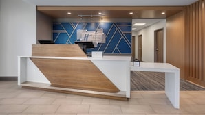A reception desk with a modern design, a sign indicating it's a Holiday Inn Express, and a corridor leading to rooms. - Holiday Inn Express & Suites Courtenay - Comox by IHG (Courtenay)