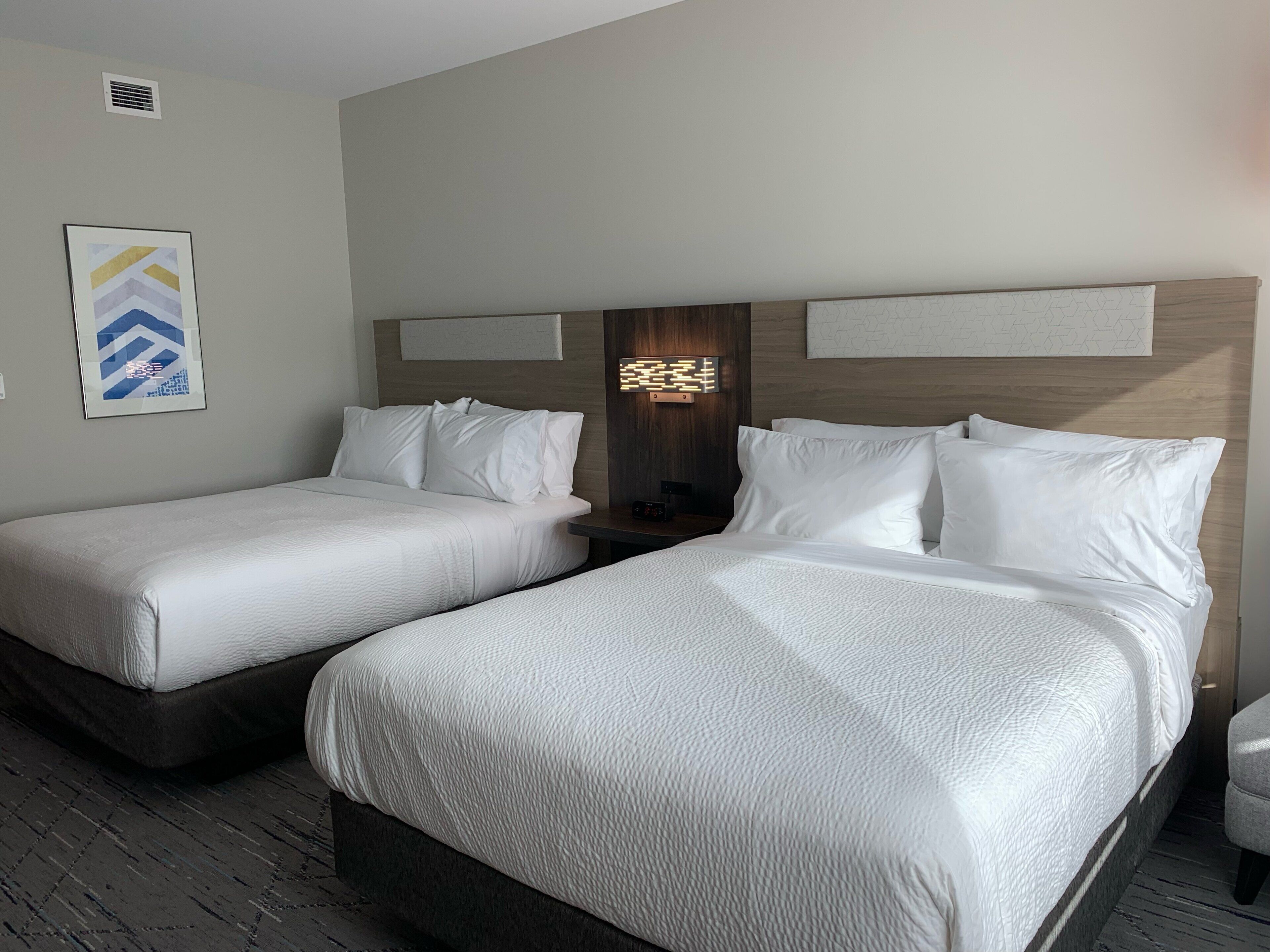 Ein Hotelzimmer mit zwei Betten, einem Nachttisch und einer Wandleuchte.
