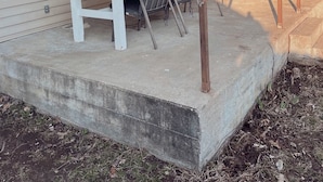 A covered patio area with a concrete platform, a table, and chairs. - Stockton Lakes’ Rustic Retreat - Cozy & Close (Stockton)