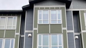 Un immeuble résidentiel à plusieurs étages, doté d’une entrée de garage, portant les numéros 120 et 13, et dont la façade est en pierre.
