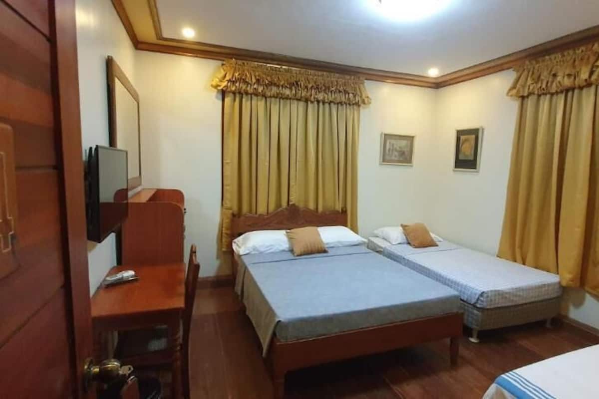 A hotel room with two beds, a desk, a chair, and a television.