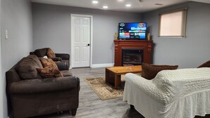A living room with a brown leather sofa, a white sofa, a wooden coffee table, and a fireplace.