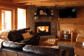 Una sala de estar acogedora con chimenea de piedra, sofá de cuero, estanterías de madera y televisor de pantalla plana.