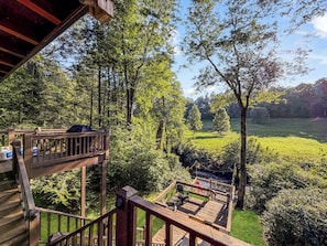 Um deck de madeira com vista para uma floresta e um campo.