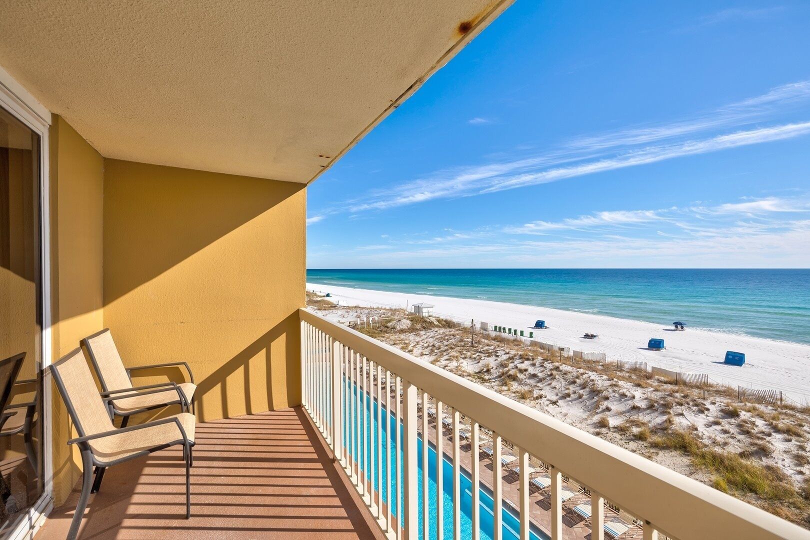Un balcón con vista a la playa y una piscina.
