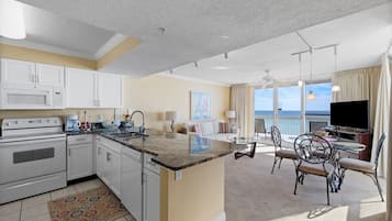 Una cocina moderna con armarios blancos, encimera de granito y un comedor con mesa y sillas redondas.