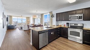 A modern kitchen with dark cabinets, stainless steel appliances, and a large island. - Terrace at Pelican Beach 1101 3 Bedroom Condo by Pelican Beach Management (Destin)