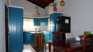Eine Küche mit blauen Schränken, einem Holzespeise Tisch und einem schwarzen Kühlschrank.