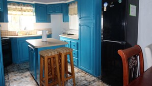Eine Küche mit blauen Schränken, einem schwarzen Kühlschrank und Holzstühlen.