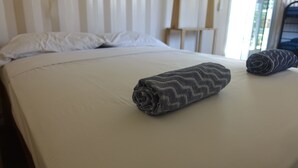 A neatly made bed with a rolled-up towel and a pillow. - Casa Maya Eco Lodge (San Juan del Sur)