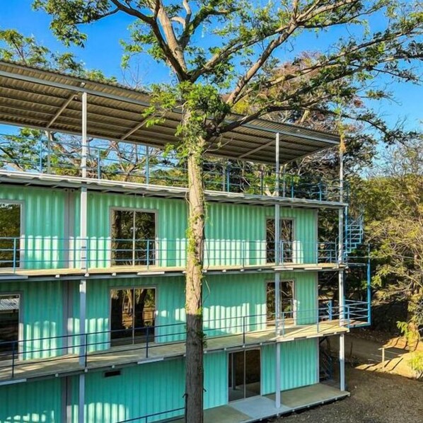 A multi-story building with green siding and a metal roof.
