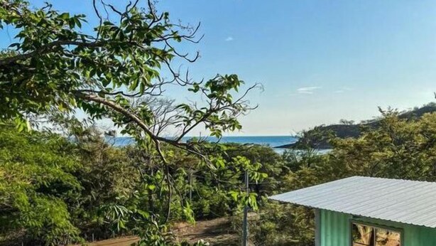 A green building with a corrugated metal roof, a staircase, and a view of the sea. - Casa Maya Eco Lodge (San Juan del Sur)