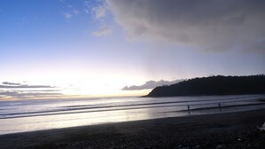 A beach with a clear sky, calm sea, and a distant hill. - Casa Maya Eco Lodge (San Juan del Sur)